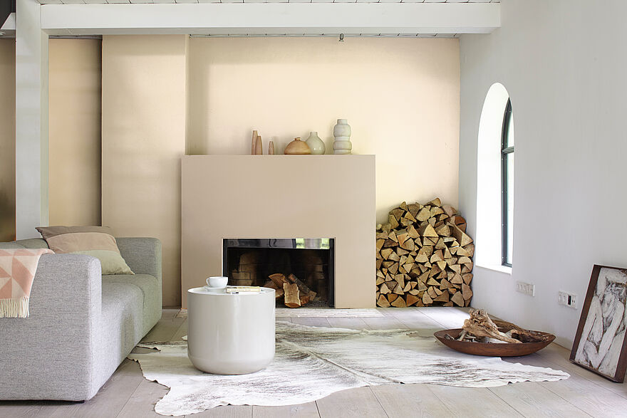 Modernes, elegantes Wohnzimmer in beigen Tönen mit Kamin und grauem Sofa mit Alpina Wandfarbe Zartes Puder.
