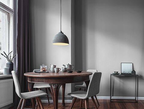 Ein gedeckter Tisch vor einer Wand in Taupe mit einem Fenster im Hintergrund