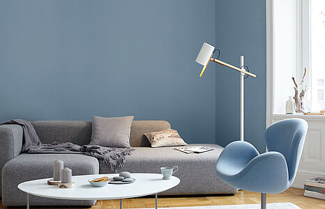 Stilles Graublau. Ein in diesem kühlen, frischen Farbton gestrichenes Wohnzimmer mit grauer Couch, Couchtisch und Sessel.