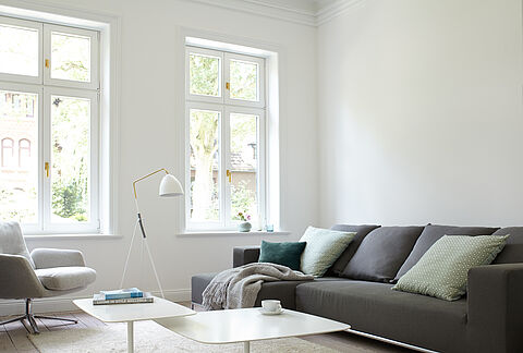 Helles, modernes Wohnimer mit grau-braunem Sofa vor einer weißen Wand.