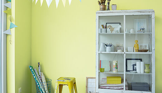 Weiße Vitrine mit Dekoobjekten vor hellgrüner Wand. Shabby Chic: von kühl bis feminin